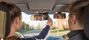 Leerling en instructeur kijken in de binnenspiegel van de auto