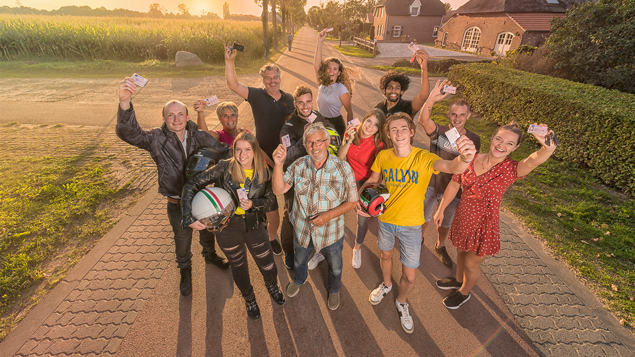 Geslaagden leerlingen bij elkaar die een rijbewijs aan de camera laten zien