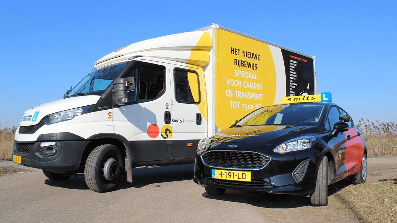 De camper van Smits Opleidingen samen met een lesauto